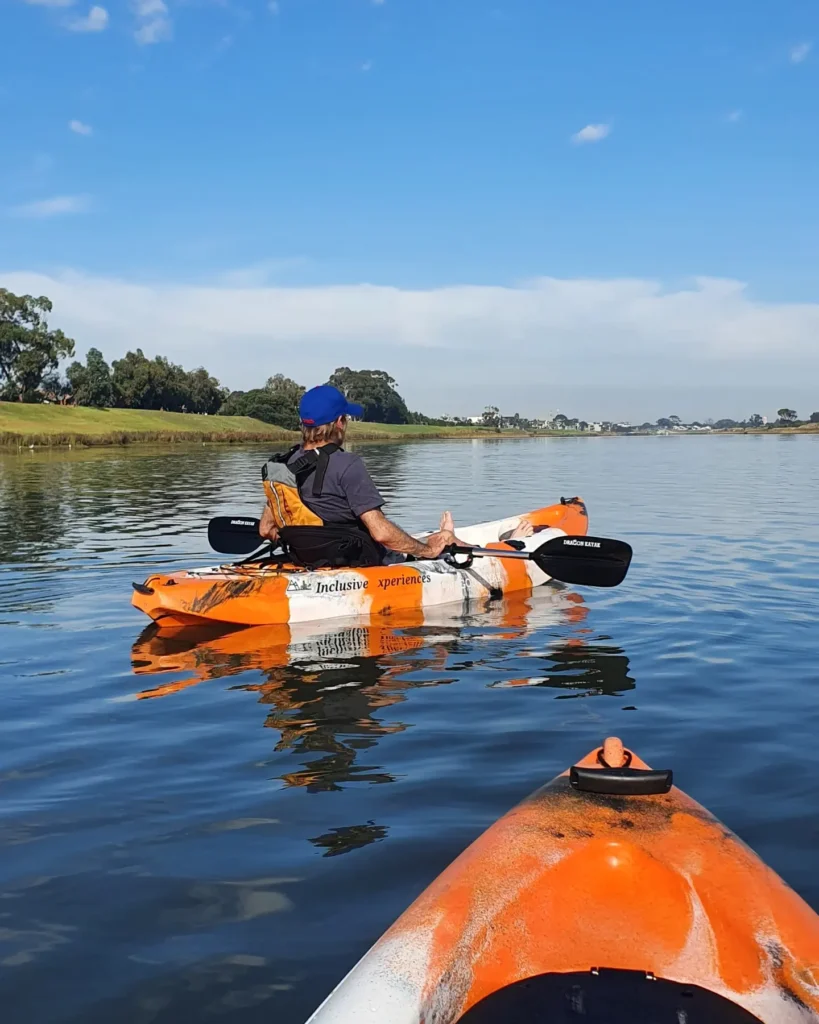 view of a person paddling a kayak on a river with the nose of a kayak in the foreground